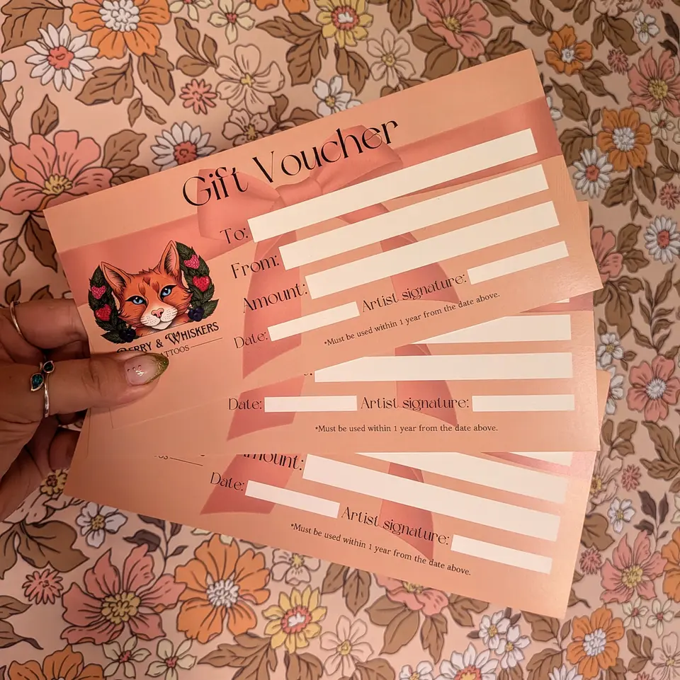 A hand holding printed Berry & Whiskers gift vouchers against retro floral wallpaper