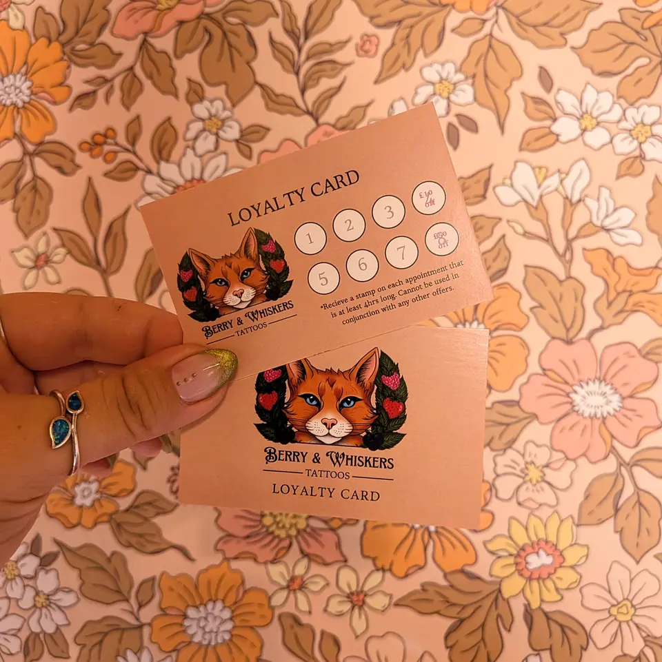 Printed Berry & Whiskers loyalty cards with eight stamp circles, held against retro floral wallpaper